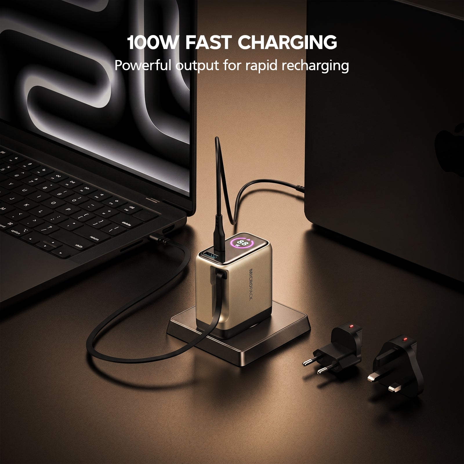 100W fast charging adapter with laptop on a dark surface