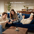 Three people sitting on a couch using smartphones with a charging station on a table.