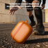 Orange carrying case with text about reinforced corner protection on a concrete surface.