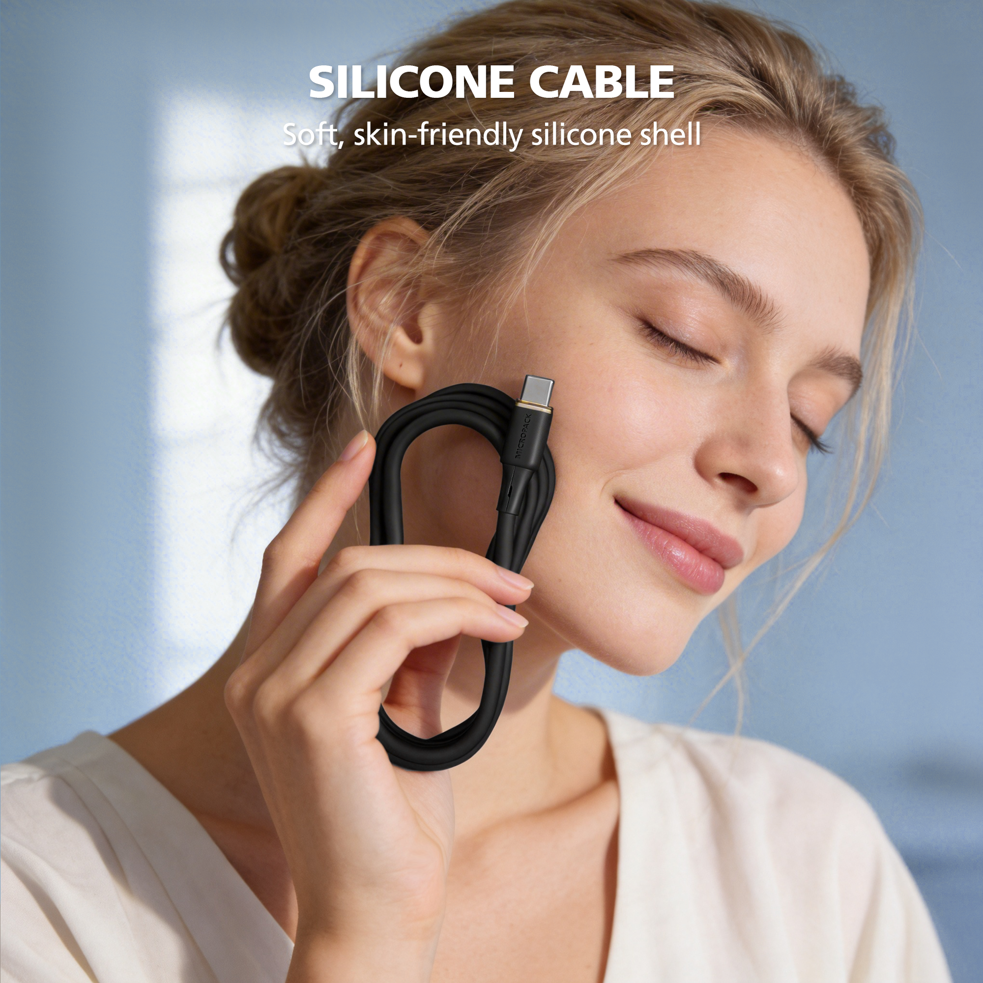 Woman holding a black silicone cable near her face with a blue background