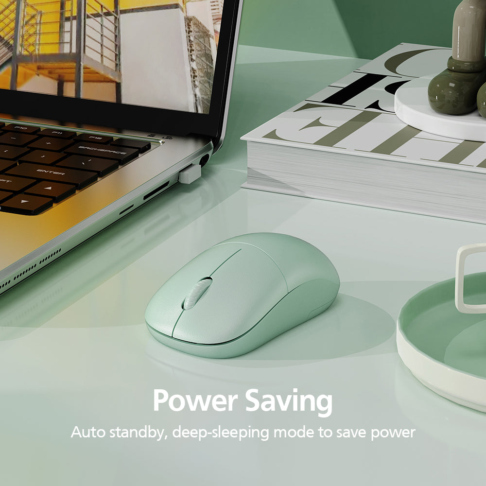 A mint green wireless computer mouse on a glossy desk next to an open laptop, with a book and small decor in the background. Text on the image reads 'Power Saving' and 'Auto standby, deep-sleeping mode to save power.