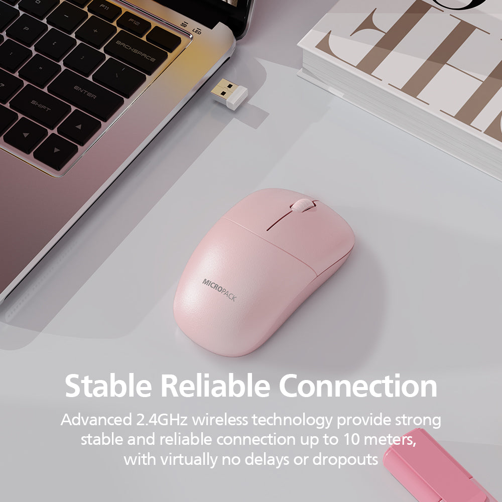 A light pink wireless computer mouse on a light gray desk surface, styled with a laptop corner, a USB receiver, a book, and promotional text reading 'Stable Reliable Connection' and 'Advanced 2.4GHz wireless technology provide strong stable and reliable connection up to 10 meters, with virtually no delays or dropouts.