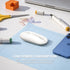 White mouse on a blue mouse pad with office supplies on a desk