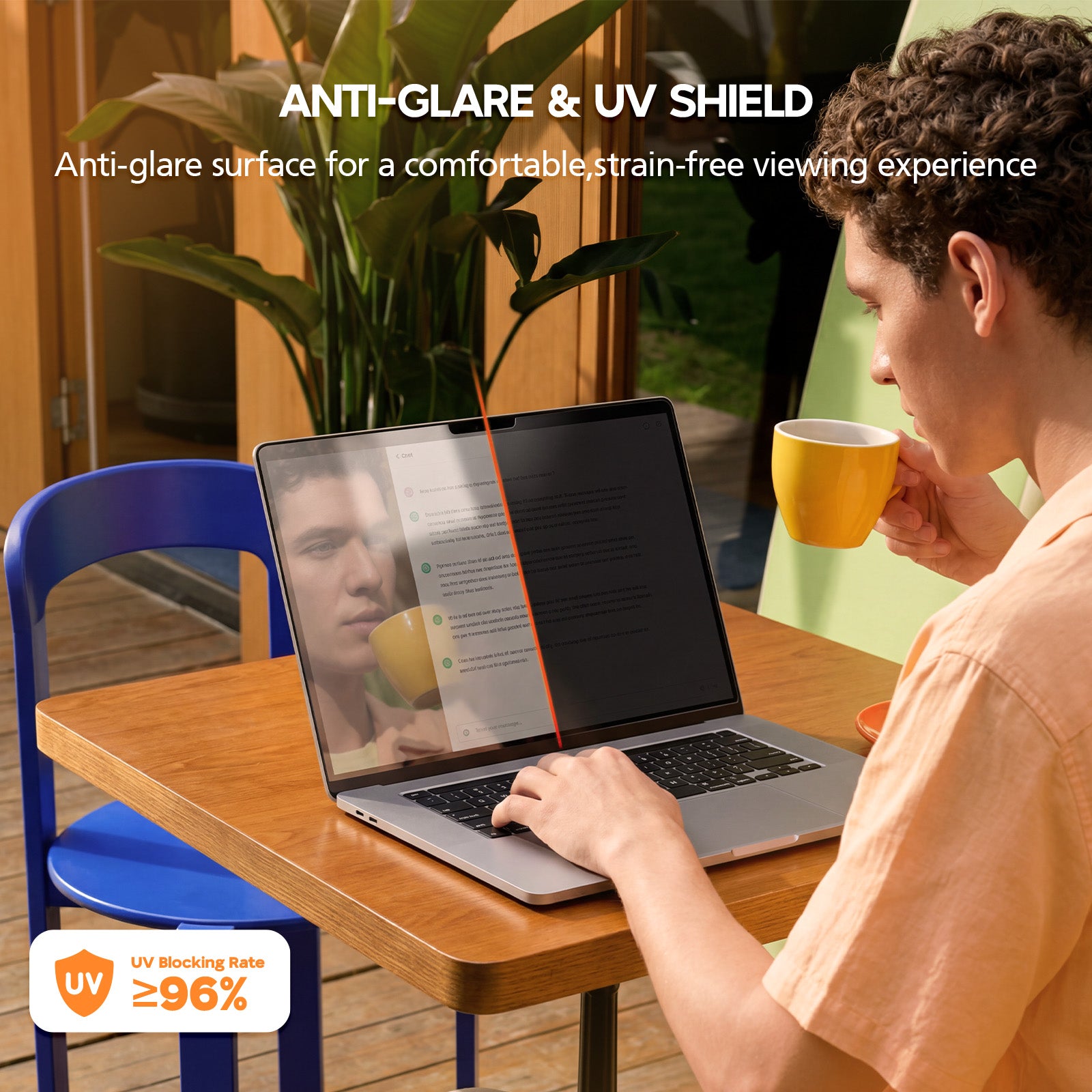 Person using a laptop with an anti-glare and UV shield feature, sitting at a table with a cup of coffee.