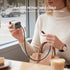 Person holding a retractable USB-C cable and charger in a cafe setting