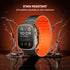 Smartwatch with an orange band on a reflective surface with water splashes, emphasizing stain resistance.