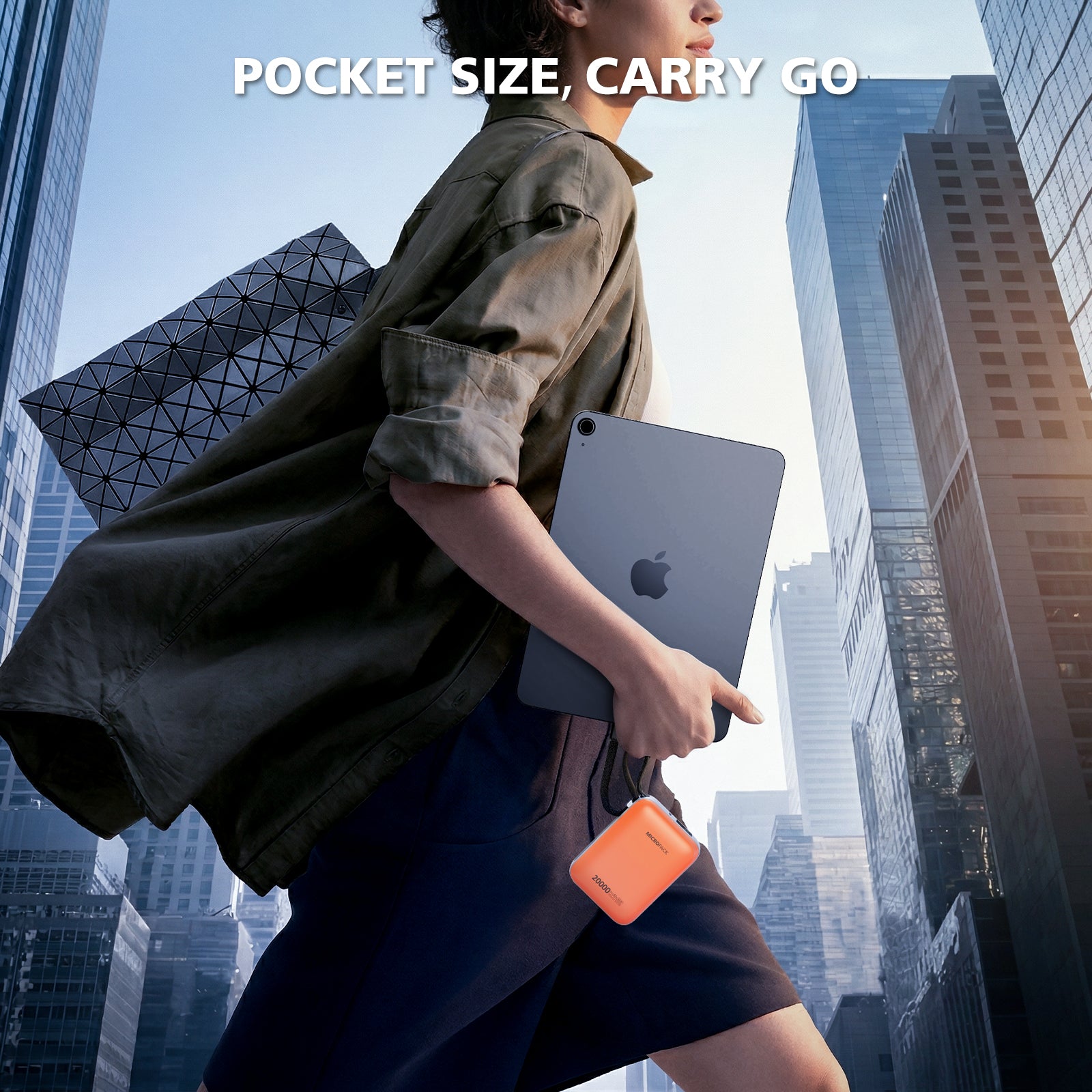 Person holding a tablet and phone case in an urban setting with skyscrapers.